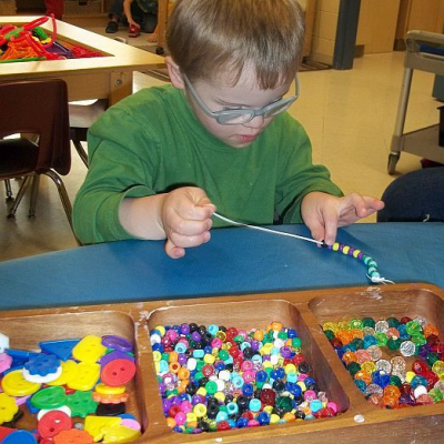 young boy putting beads on a string