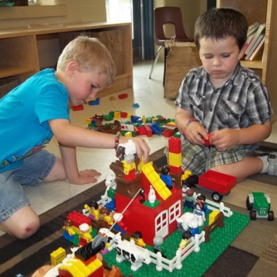 two young boys playing with a lego building