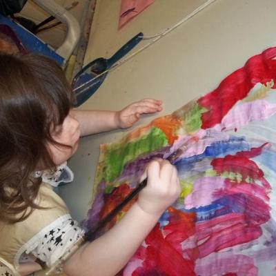 young girl painting with red paint