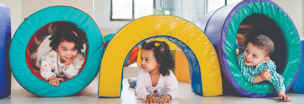 three young children playing inside soft childrens structures