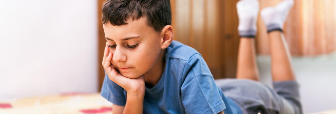 male child on bed looking at book