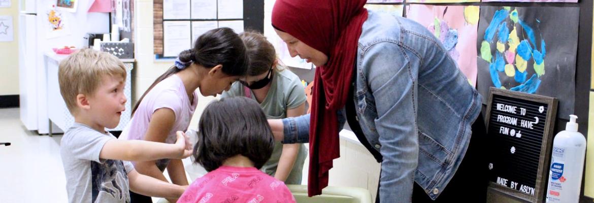 educator playing with children at water sensory table