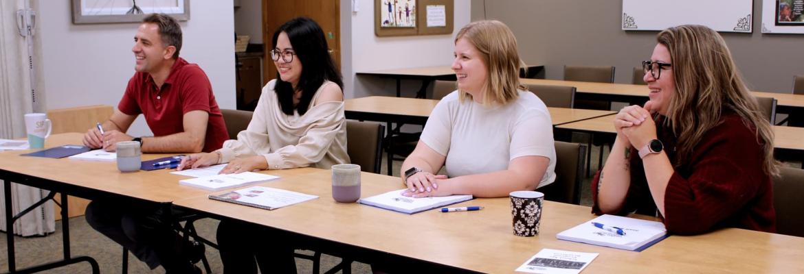 four multicultural educators sitting at long table in orientation